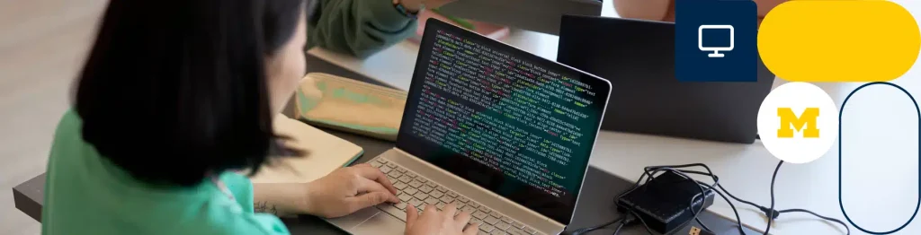 Person coding on a laptop with University of Michigan logo in the background